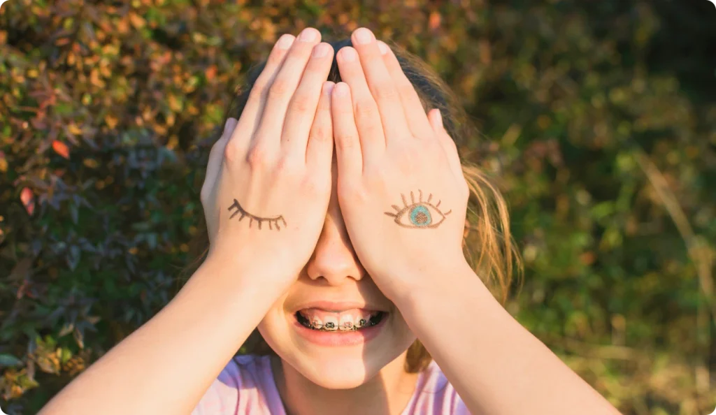 Fillette qui se cache les yeux en souriant